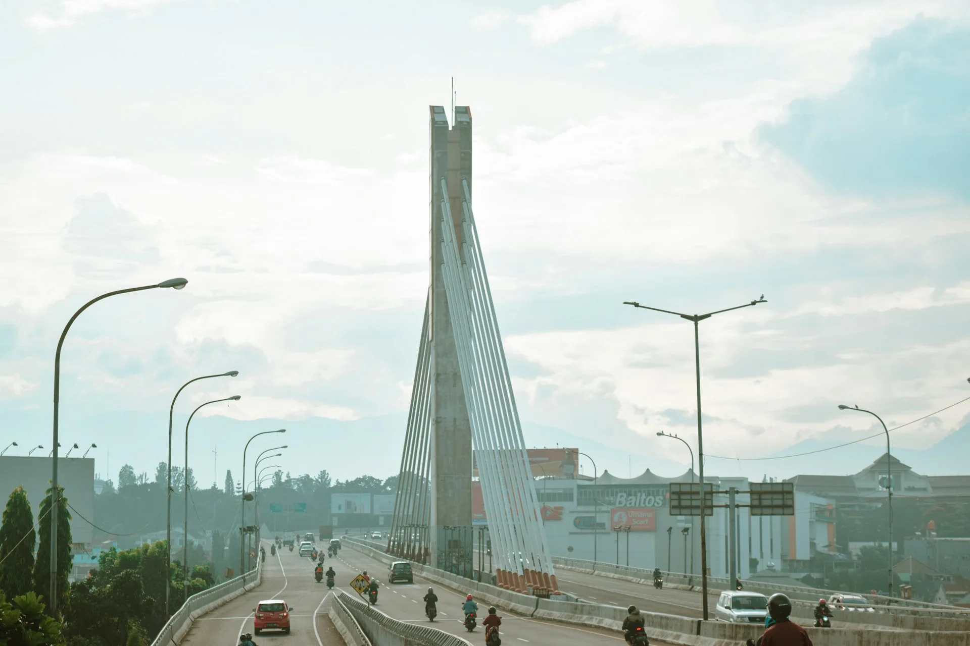 Kendaraan melintas di jalan dekat jembatan pada siang hari
