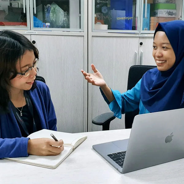 Seorang perempuan bekerja menggunakan laptop di meja