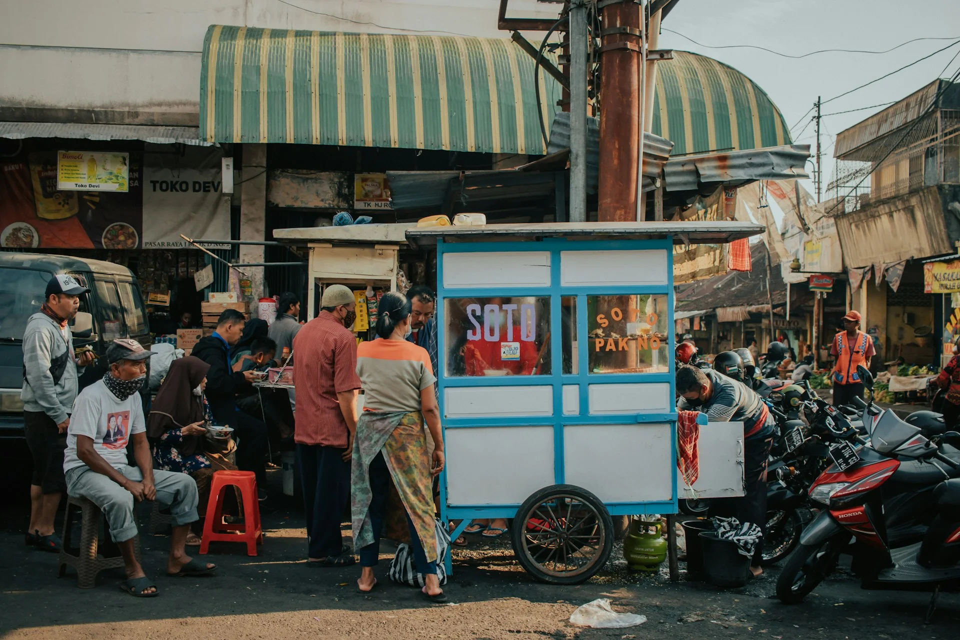 Beberapa orang berada di dekat kios makanan berwarna biru dan putih