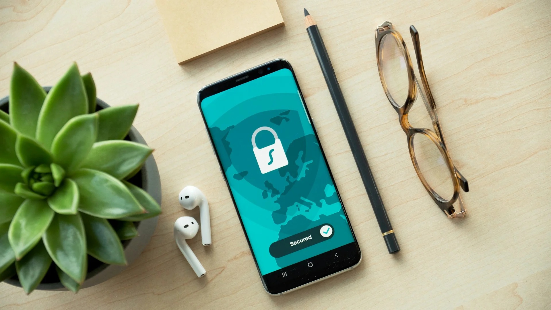 A smartphone displaying a security lock icon on a wooden desk with a succulent A smartphone displaying a security lock icon on a wooden desk with a succulent