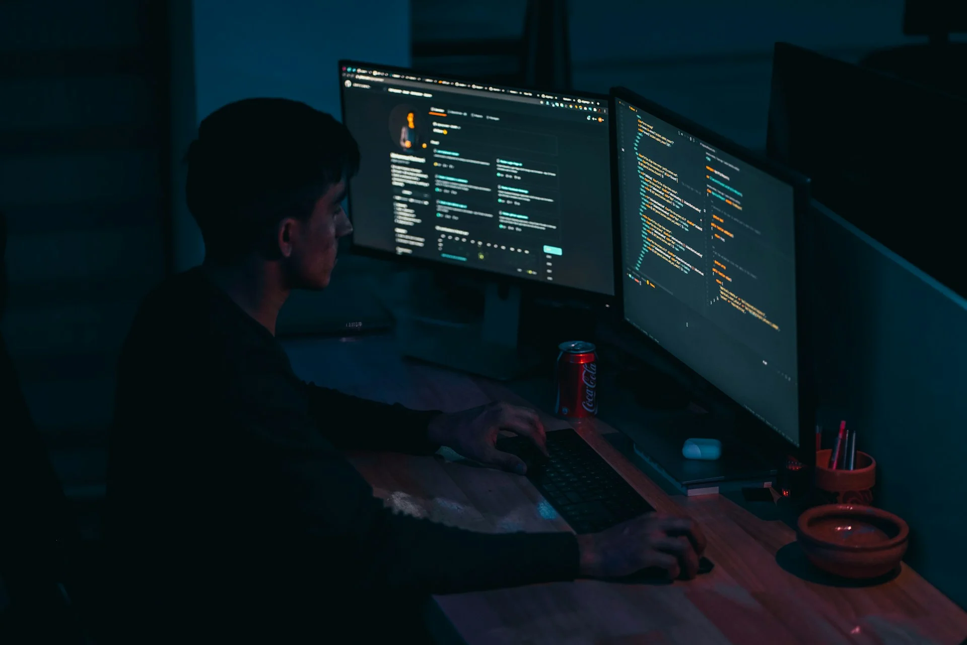 Seorang pengembang berbaju hitam bekerja di depan monitor komputer