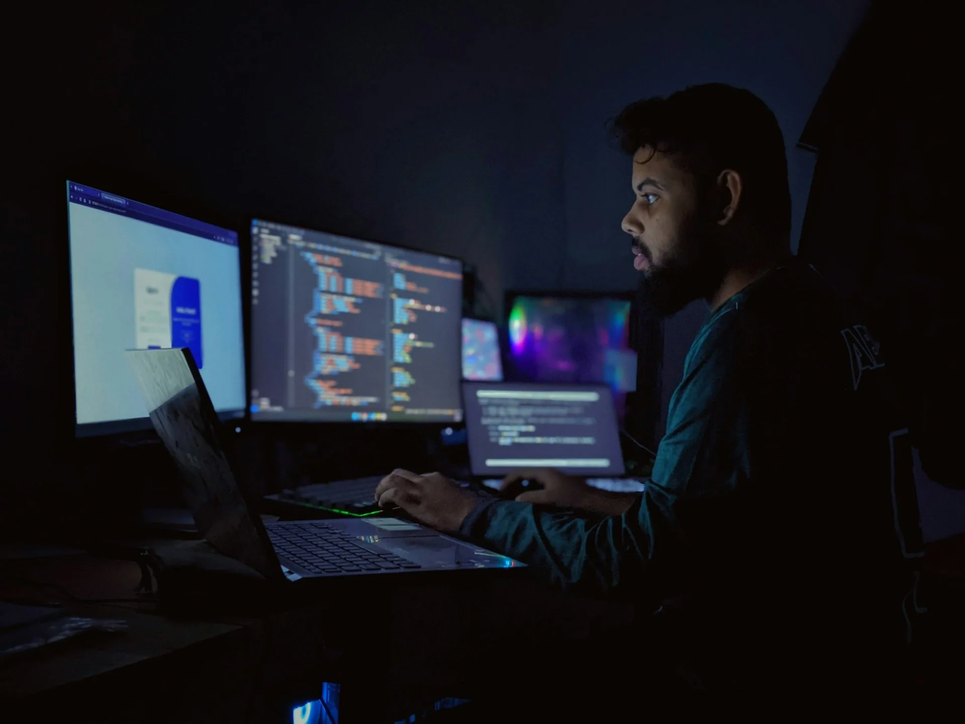 Seorang pengembang bekerja di depan tiga monitor komputer