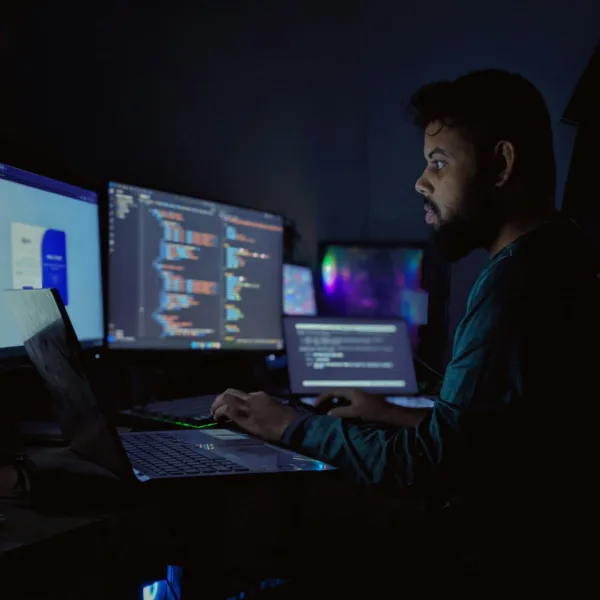 Seorang pengembang bekerja di depan tiga monitor komputer